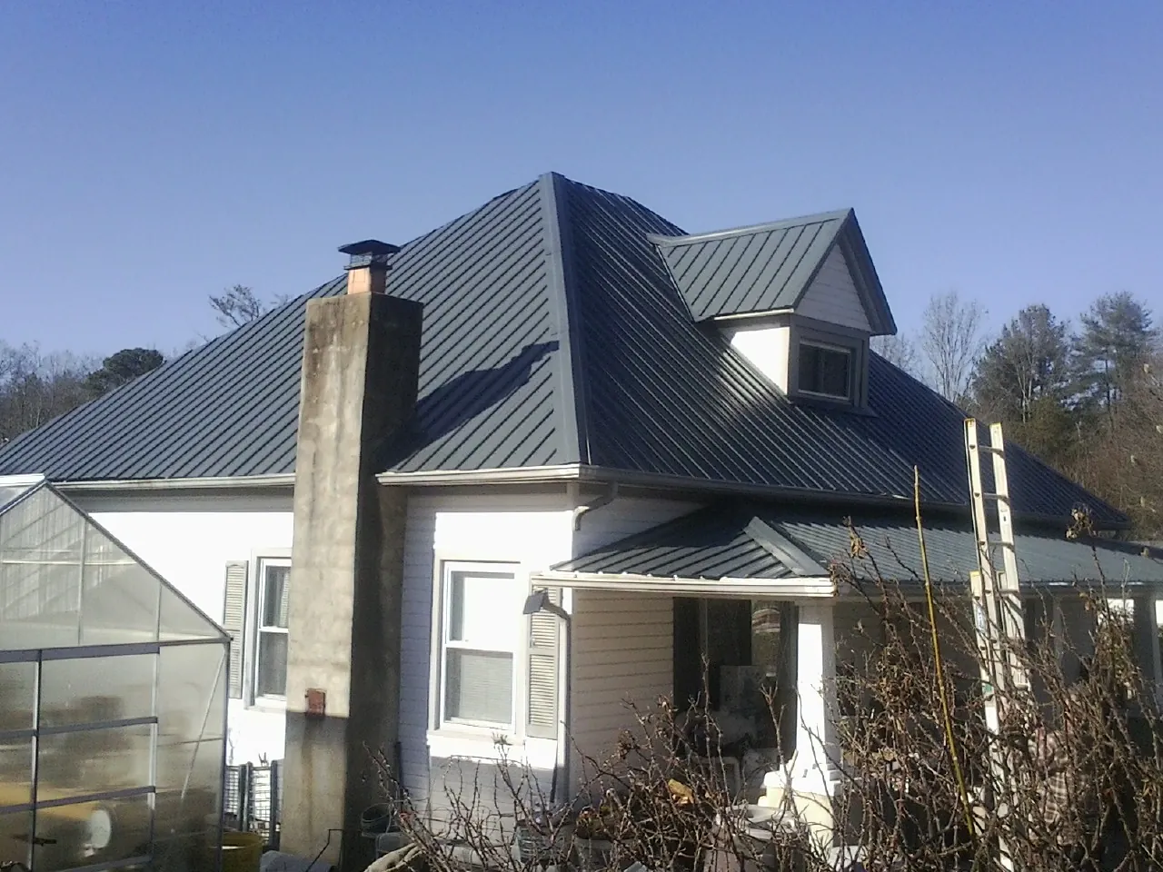 Dark blue standing seam metal roof on a white farmhouse with dormer — Slate & Tile Roof Repair by Roofing Brothers in Rockdale