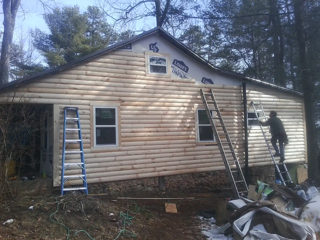 Ladders set against fresh log siding during an exterior remodel in Rockdale