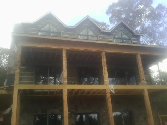 Dormers and porch framing on a large log home under construction — Roof Coating work by our crew in Rockdale