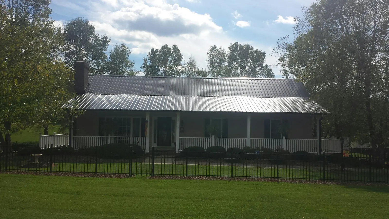 Gray metal roof on a brick ranch with a full width front porch — Gutter Guard Installation work by our crew in Rockdale