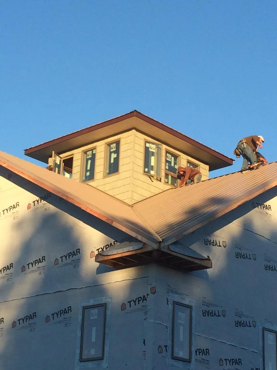 Roofers working around a rooftop cupola on a new metal roof at sunset — Roof Waterproofing in Rockdale by Roofing Brothers